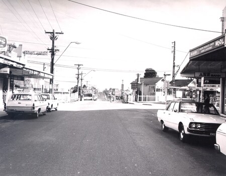 The level crossing gates at Highett are open and there is a clear view along Highett Road.