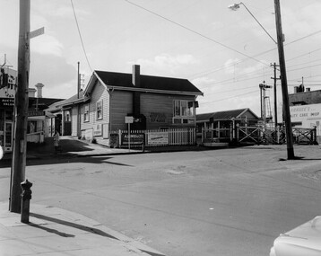 The weatherboard station house next to the open level crossing gates.
