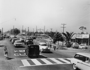 Cars travelling along Nepean Highway with level crossing in the background.