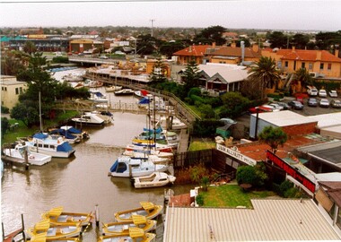 Looking inland along Mordialloc Creek with boats moored either side of the creek