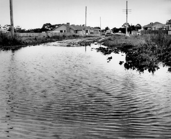 An enormous puddle leading up to an unsealed suburban street shows the inadequacy of the drainage system in Beaumaris during in 1958