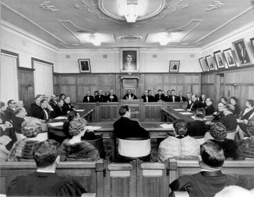 Men and women dressed in formal attire attend a ceremonial sitting of council