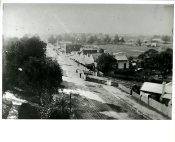 An aerial view of Charman Road, Cheltenham featuring unsealed roads, a level crossing and a shopping strip.