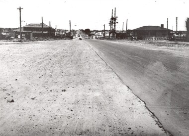 The wide gravel shoulder beside the road makes the road look wider than it is