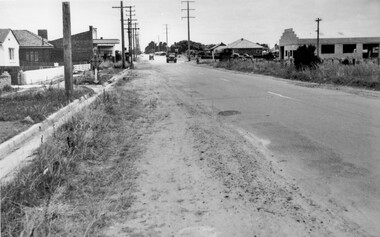 A road in poor condition runs through a fairly newly established suburban area