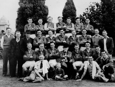 Four rows of men grouped together with most wearing a football playing uniform