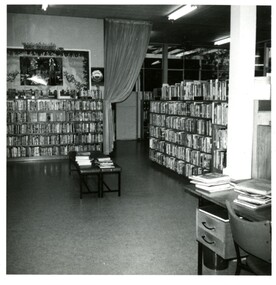 View of library interior with full bookshelves and corner of a desk at right