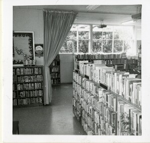 A photograph of the interior of a library with books on shelves and a sign that reads 'TEENS CORNER'
