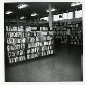 A view of a library interior with a man standing looking at the shelves