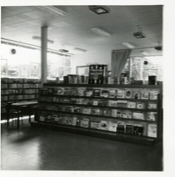 A blurred photograph of a display shelf in the library with a sign above advertising Storytime