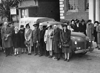 A group of men and women standing in front of, and behind a utility vehicle
