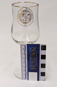 Red wine glass with gold edge and City of Moorabbin logo including Nautical Archaeology scale to 8cm placed against right side