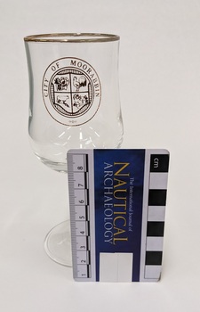 White wine glass with gold edge and City of Moorabbin logo including Nautical Archaeology scale to 8cm placed against right side