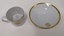 White cup and saucer with gold edging and City of Moorabbin logo, separated