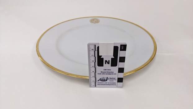 White dinner plate with gold edging and City of Moorabbin logo with scale to 8cm placed against right-hand side