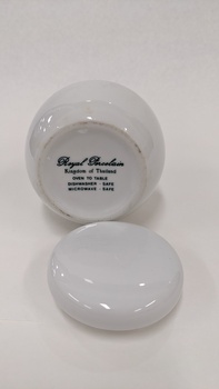 Base of small white sugar bowl with lid removed and placed at front