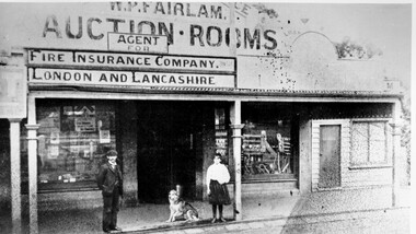 Black and white image of a man, girl and dog outside a shop