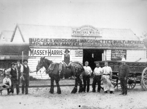 A group of men, with a Clydesdale horse, standing in front of a shop.
