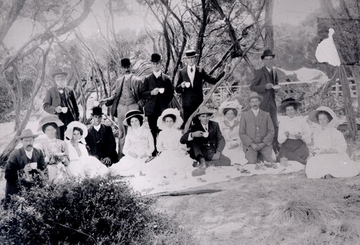 A group of men and women having a picnic in a seaside setting