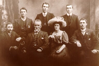 Family of six men and one woman sitting together, posed for a photograph
