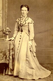 Mrs Isabella McDonald standing beside a table