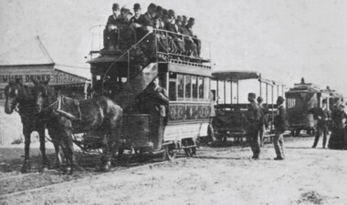 A loaded horsedrawn tram is being pulled along the street.