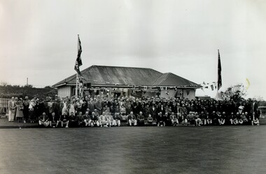 A large gropu of people posing in front of the Cheltenham Bowling Club clubhouse