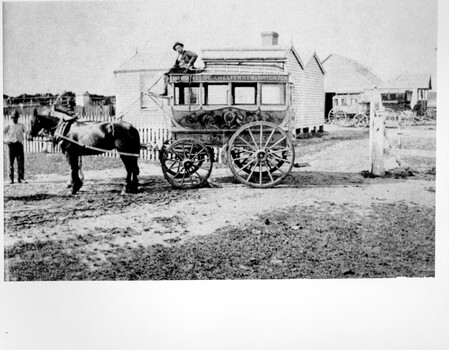 Horse drawn wagon with a man sitting on top holding the reins 