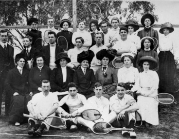 A group of men and women with rackets on the sidelines of a tennis court