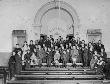 Black and white image of boys standing on a a church alter and front row pews holding fife and drums