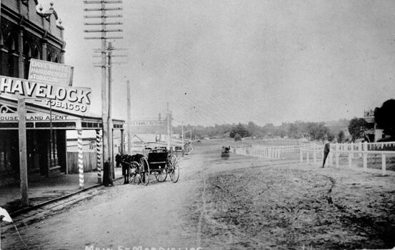 Black and white image of Main Street, Mordialloc. Horse and carriage are parked to the left with a Havelock Tobacco sign over the porch of the buildings to the left