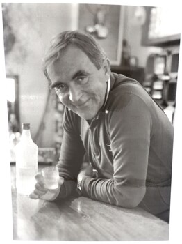 Portrait of Ory Frueaf standing at the bar with a glass of vodka in his hand.