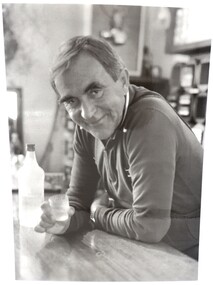 Portrait of Ory Frueaf standing at the bar with a glass of vodka in his hand.