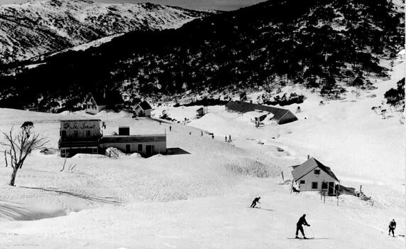 Photo of the lodge buildings from above, A small number of skiers are on the slopes,