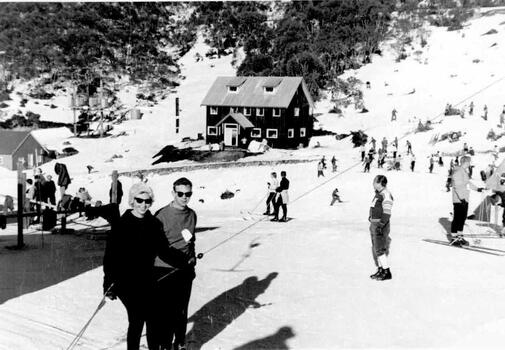 A couple holding onto the tow rope at Falls Creek. Lodge in the background