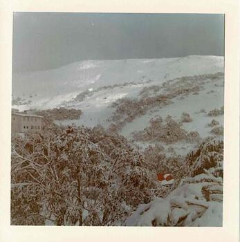 Snow covered hills with lodge on the middle left of the photo
