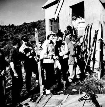 A group of people with skis at the  front of the hut