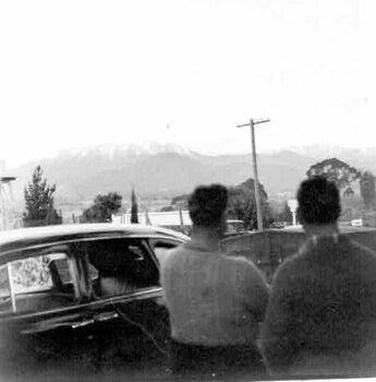Views towards Frying Pan. Two men and a car in the foreground. Location unknown.