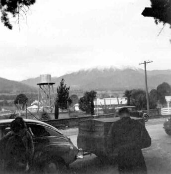 Views towards Frying Pan. Two people and a car in the foreground. Location unknown.