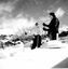 Two women on skis surrounded by snow. Ominous clouds overhead