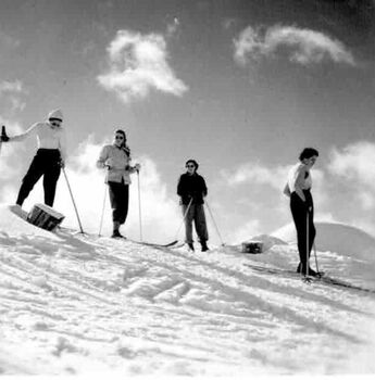 Group of skiers standing at the top of a slope.