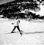 Woman facing downhill on skis. Trees in the background.