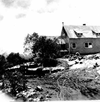 Mountain lodge. Trees and muddy track in the foreground.