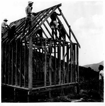 Men standing on top of lodge securing the roof framework in place.