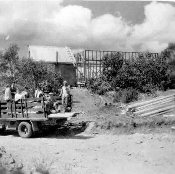 Partly constructed building and group of men and a truck