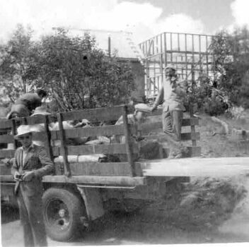 Group of men unloading truck in front of partly constructed building