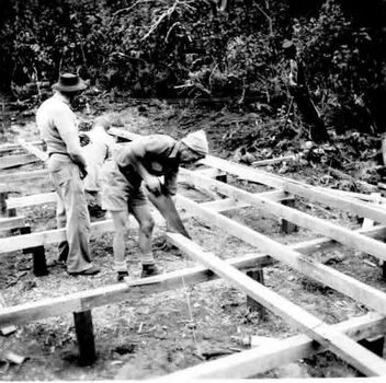 Three men laying timber for the floor frame