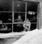 Two women looking out of the window of the Lodge. Snow is piled up to the window sill.