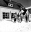 Five people with skis in front of lodge in heavy snow