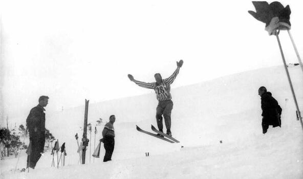 Ski Jumper wearing number 28 with officials or observers standing on either side